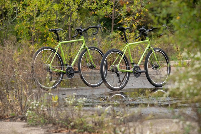 Two Surly Disc Trucker bikes in Pea Lime Soup color side by side with one slighty ahead on wet muddy trail in a prairie