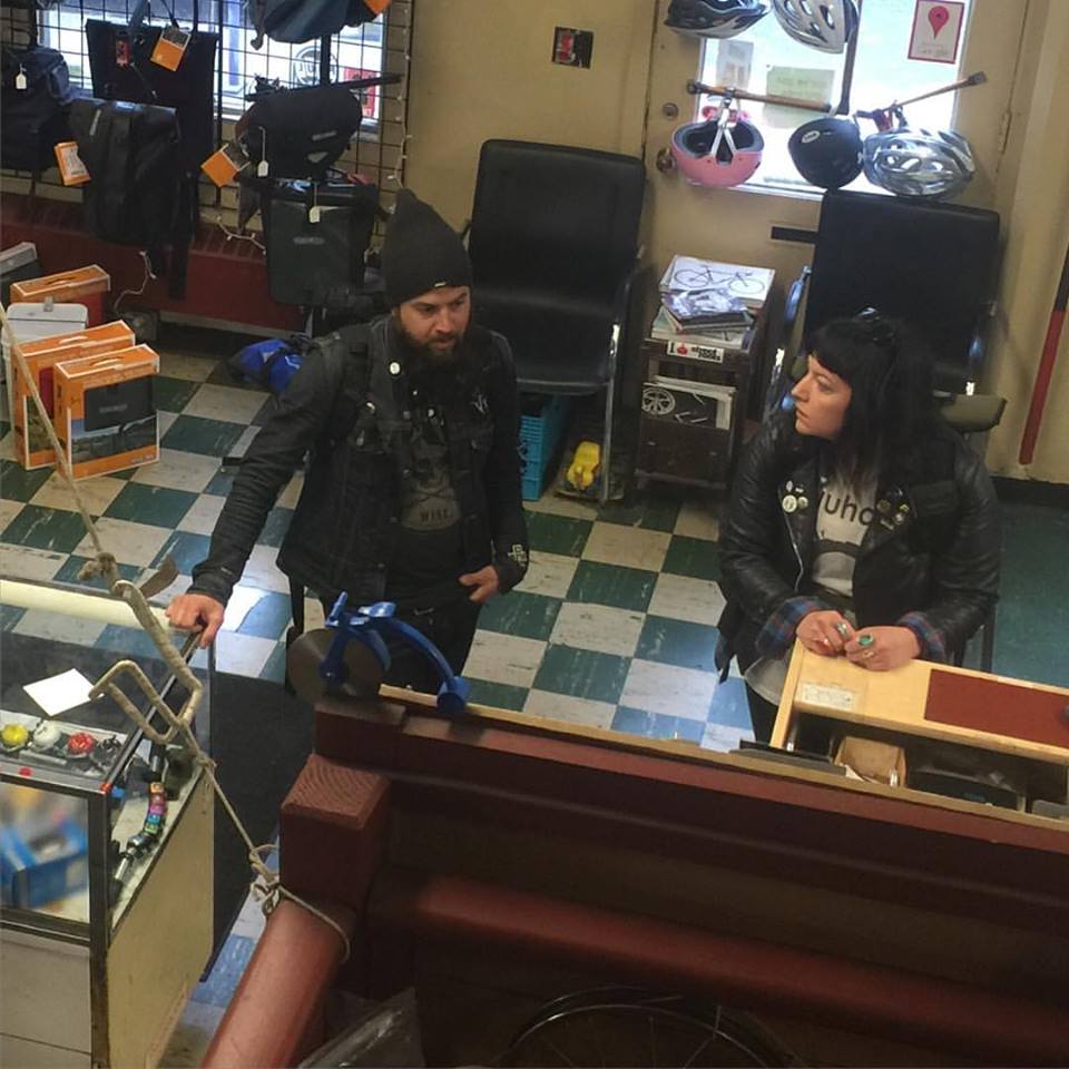 Front view of 2 people standing at the counter of a bike shop