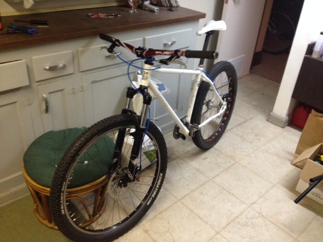 Left side view of a white Surly 1x1 bike, leaning against a floor cabinet, in a kitchen
