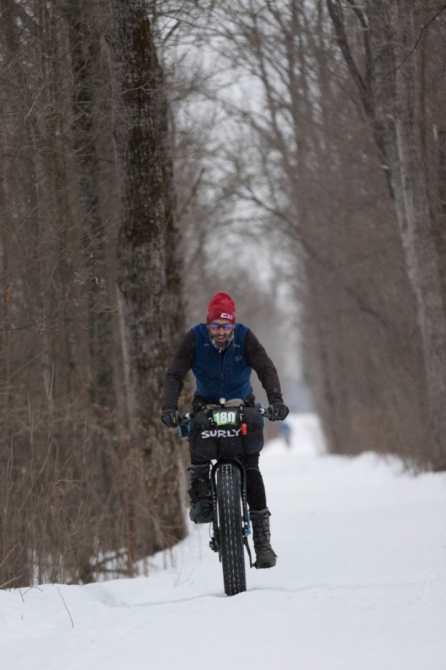 Front view of a cyclist riding a fat bike down a snow covered trail in the woods
