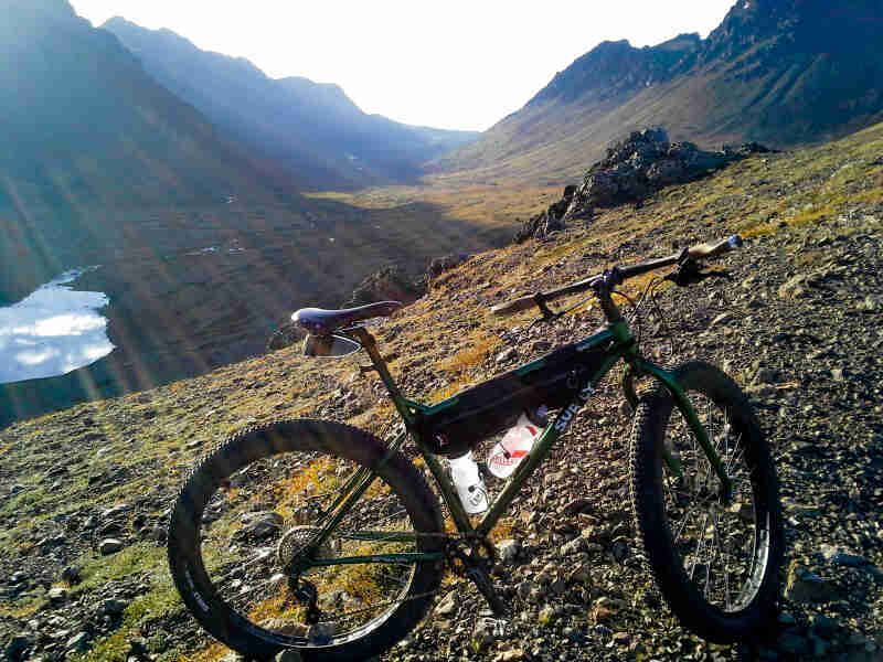 Right side view of a green Surly bike on a rocky hill in a mountain valley