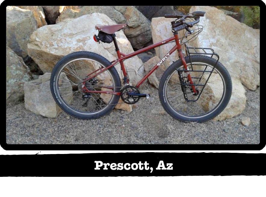 Right side view of a dark red Surly bike in front of boulders-Prescott, AZ banner below image