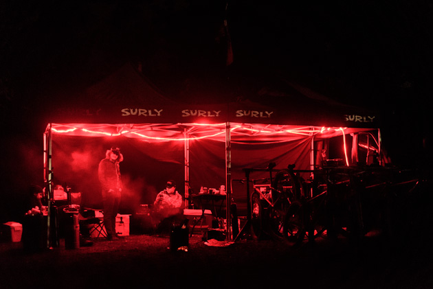 Two black Surly canopies with red string lights at night