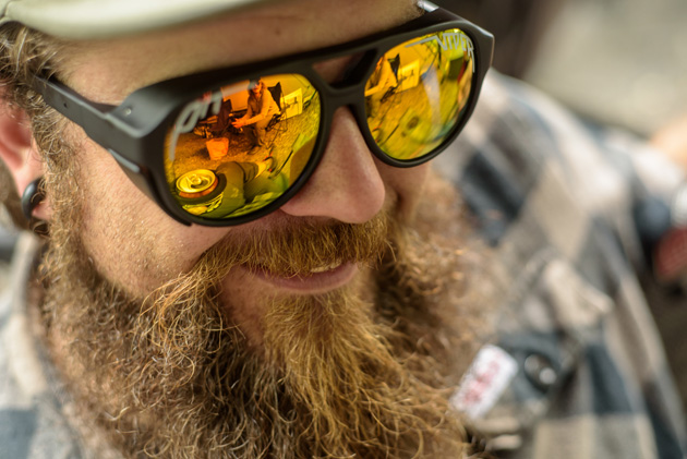 Person with a thick, red beard smiling wearing mirrored sunglasses 