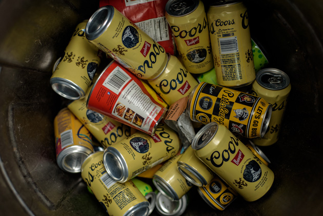 Downward view of a steel garbage can full of Coors beer cans