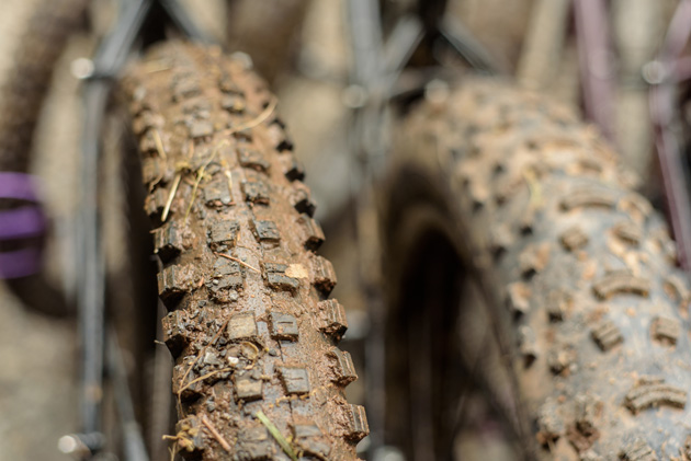 Close up front view of two knobby tire with mud in the tread