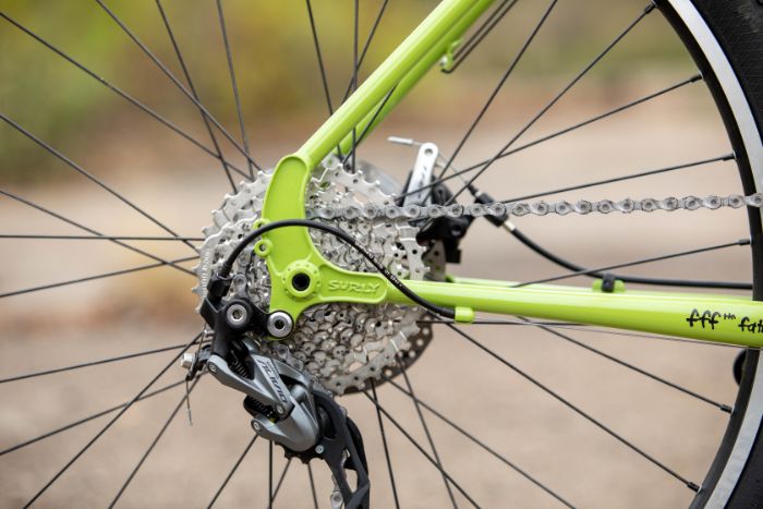 Zoom in of the back portion of a Surly Disc Trucker bike focused on rear derailleur - cassette -pulley wheels 