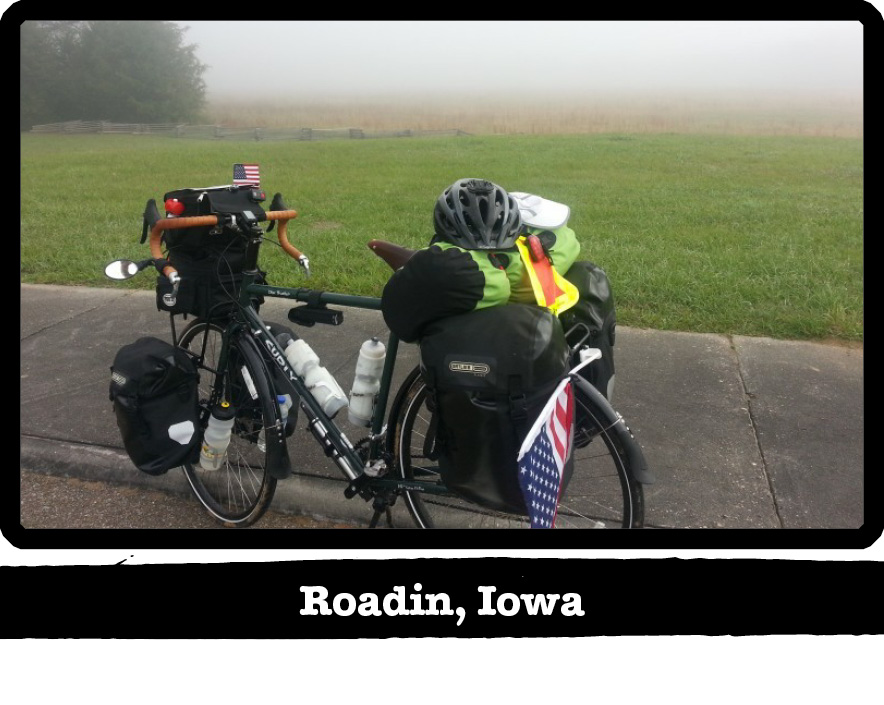 Left side view of a Surly bike loaded with gear on the side of a road, with fog behind - Roadin, Iowa tag below image