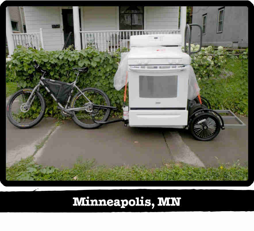 Left side view of a Surly bike pulling a stove on a trailer on a sidewalk - Minneapolis, MN tag below image