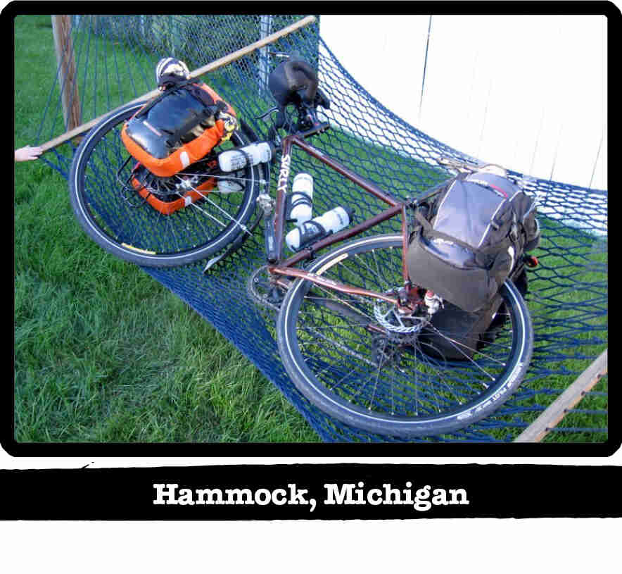 Downward left side view of a Surly bike with gear, lying in a hammock above grass - Hammock, MI tag below image