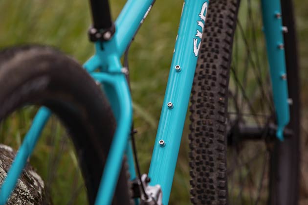 Close up of a Surly Bridge Club bike, focused on the frame's triple bottle mounts on the top and bottom of the downtube