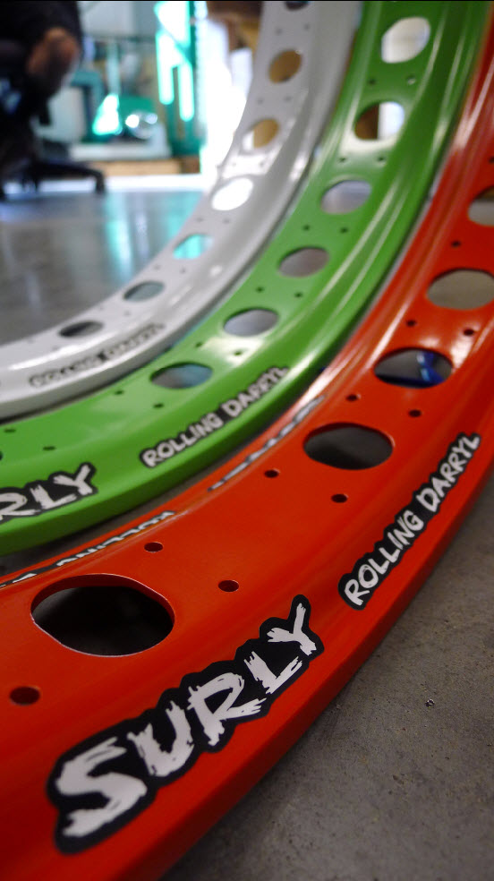 Close up,  inside view of 3 Surly Rolling Darryl fat bike rims in white, green & red, standing side by side on cement