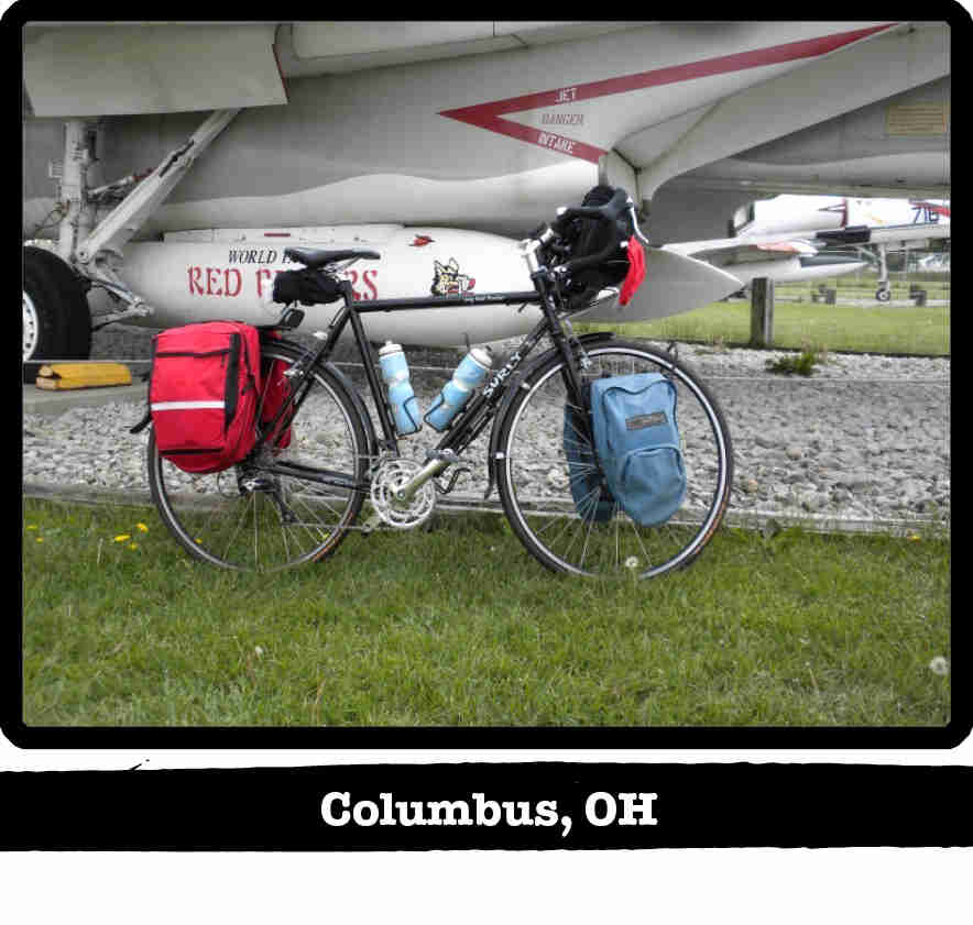 Right profile view of a black Surly Long Haul Trucker bike on grass under the wing of a jet - Columbus, OH banner below image