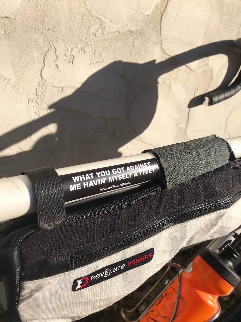 Top tube of a Surly Midnight Special bike with a gear bag and sticker leaning on tan stucco wall