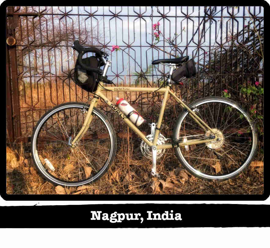 Left profile of a Surly Long Haul Trucker bike, tan, leaning of a steel rod fence - Nagpur, India tag below image