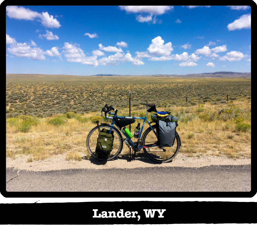 Left side view of a Surly bike on the side of the road with a wire fence and plains behind-Lander, WY banner below image