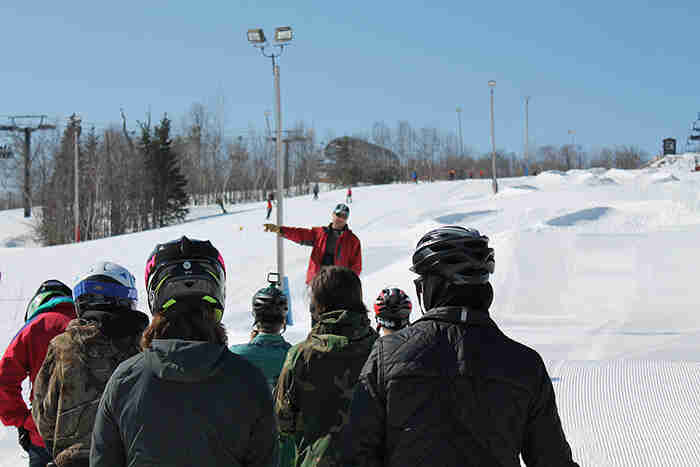 Rear view of people facing a person speaking at a ski hill