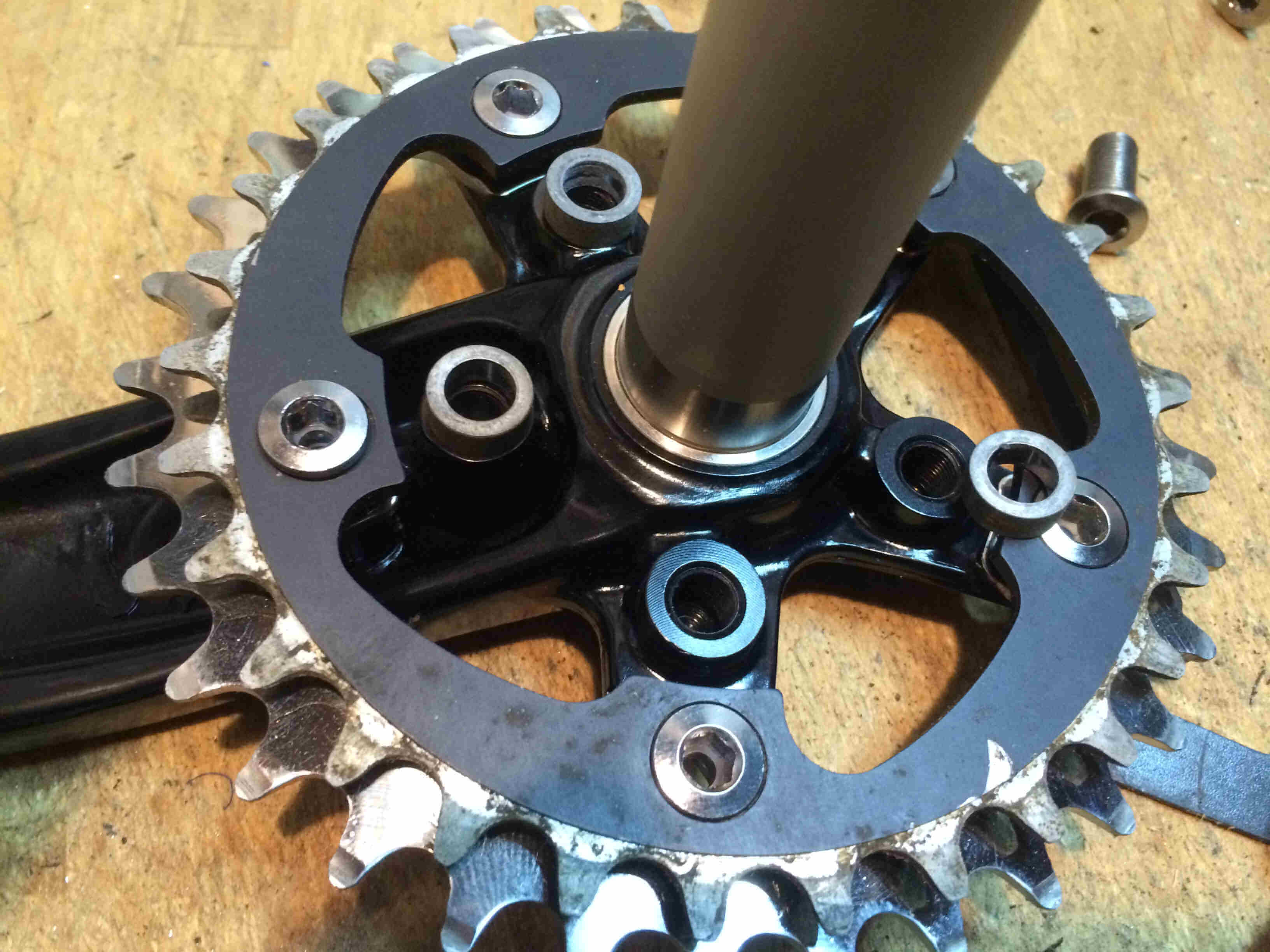 Downward, inside view of a Surly Bikes O.D Crankset, outer chainring detail, on a wood benchtop