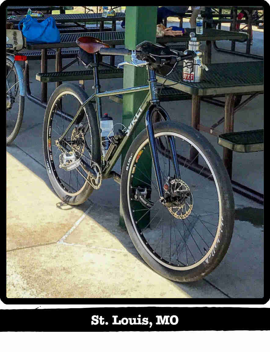 Front Left view of a Surly Karate Monkey bike, leaning on a post, under a park gazebo - St. Louis, MO tag below image