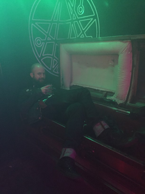 Front view of a person laying on the side of a coffin, in a dark room