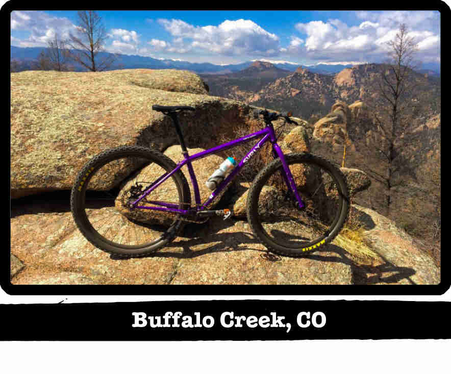 Right profile of a Surly Karate Monkey bike, purple, on a rock in the mountains - Buffalo Creek, CO tag below image