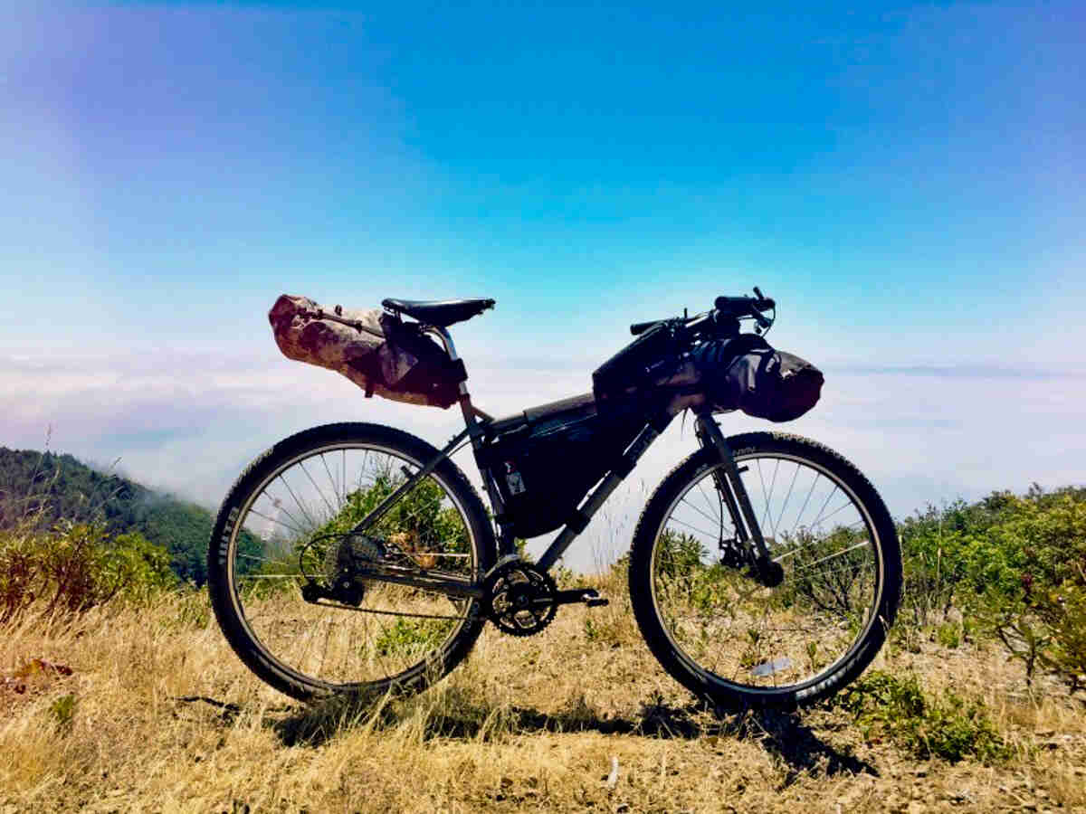 Right side view of a Surly bike, full of gear, parked on a grassy hilltop