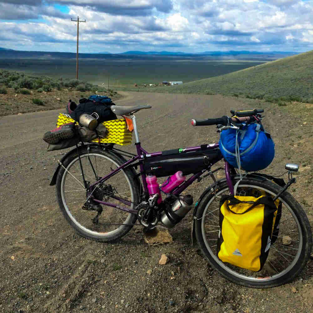 Right side view of Surly bike, loaded with gear, parked on the edge of gravel road, with plains in the background