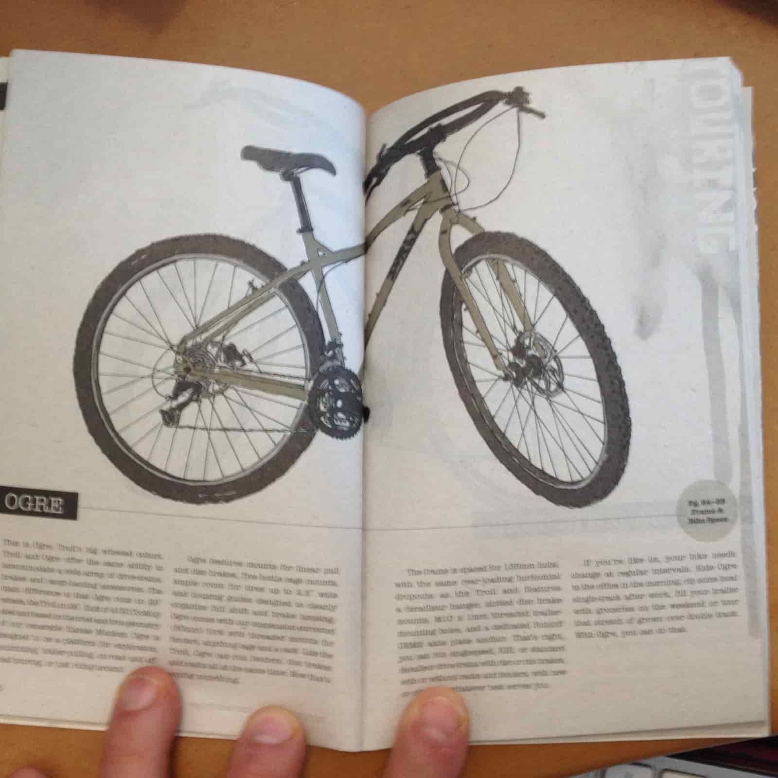 Downward view of an open catalog spread, showing a Surly Ogre bike above and text below