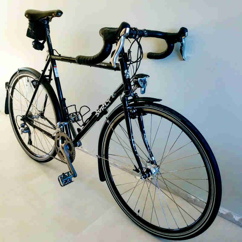 Right side angled view of a Surly Cross Check bike, black, leaning against a white wall
