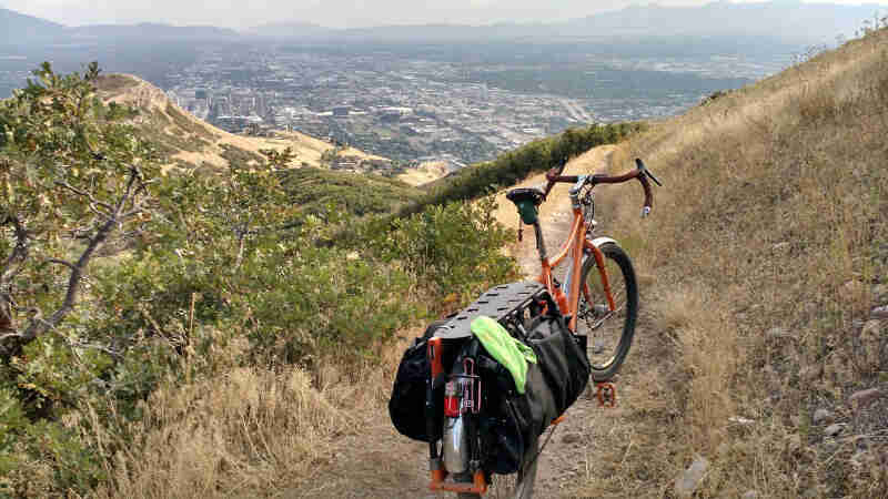 Rear view of a Surly Big Dummy bike, orange, on a dirt trail, on a mountain hill