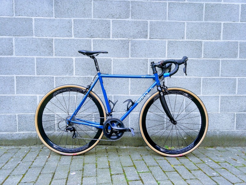 Right side view of a Surly Pacer road bike, blue, with a cinder block wall behind