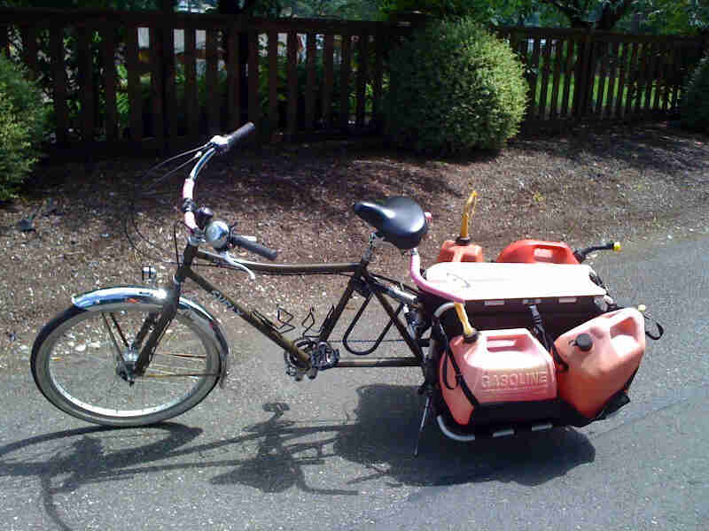 Left side view of a Surly Big Dummy bike, loaded with gas cans, parked on a paved street