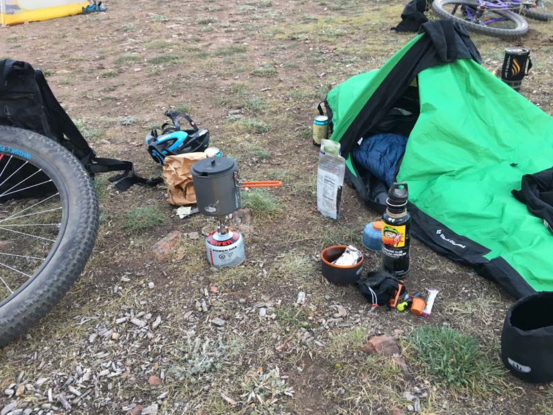 Camping gear laying on the ground, with bike laying near by