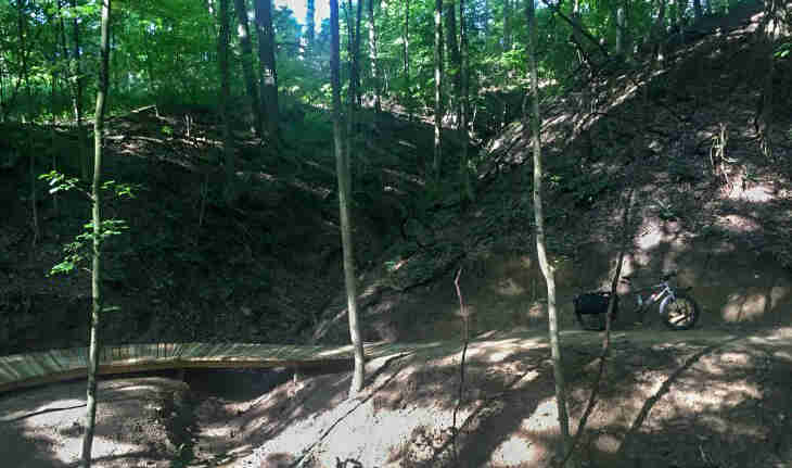 Right side view of a bike parked on a trail against a hill in the forest