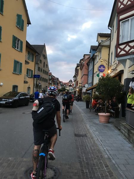 Rear view of cyclist riding down a narrow street between european style buildings