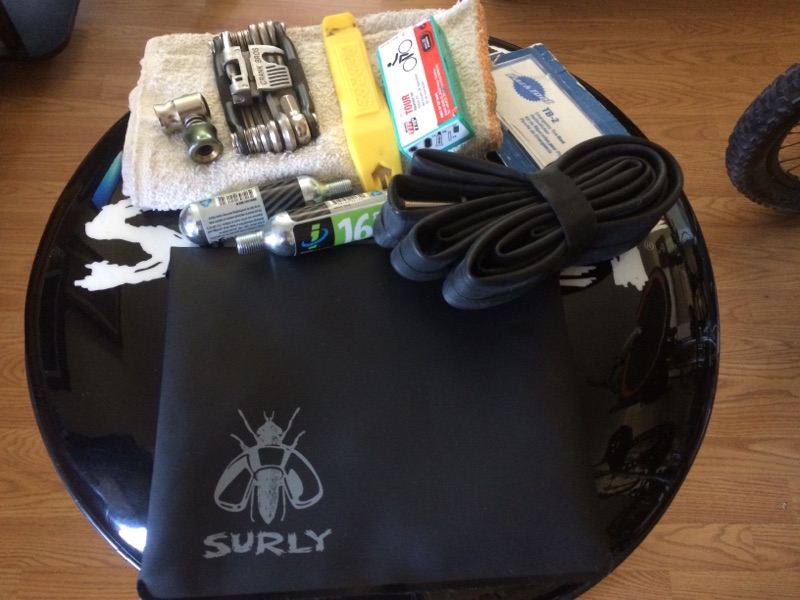 Surly tool bag, black, on top of a barstool seat, with assorted bike tools