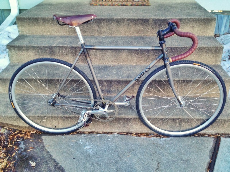 Right side view of a Surly Steamroller bike, parked at the bottom of a set of cement steps, below a front porch