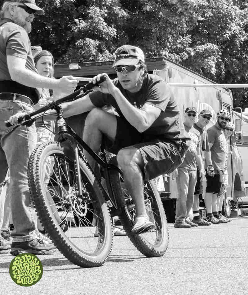 A cyclist riding a bike, seated low, new the back tire - black and white image