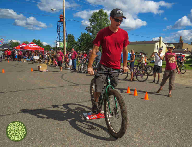 Front view of a cyclist riding a Surly Krampus bike, green, during a contest, with spectators watching in the background