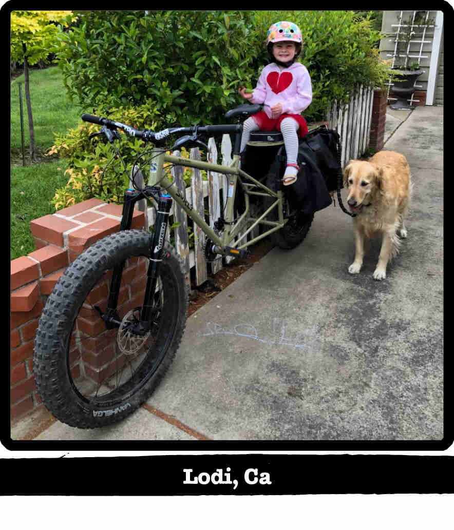 Left front view of a child sitting on the back of a Surly Bike Fat Dummy bike - Lodi, CA tag below image