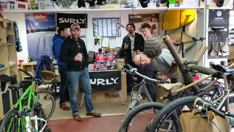 A group of five people stand in a shop with bike and a Surly banner