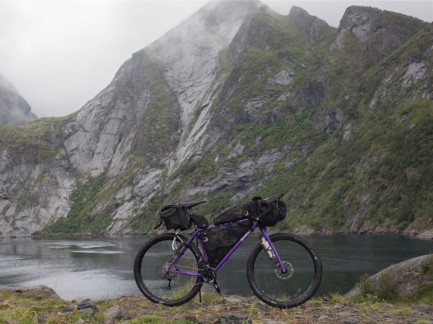 Right side view of a purple Surly bike on the edge of a lake in the mountains