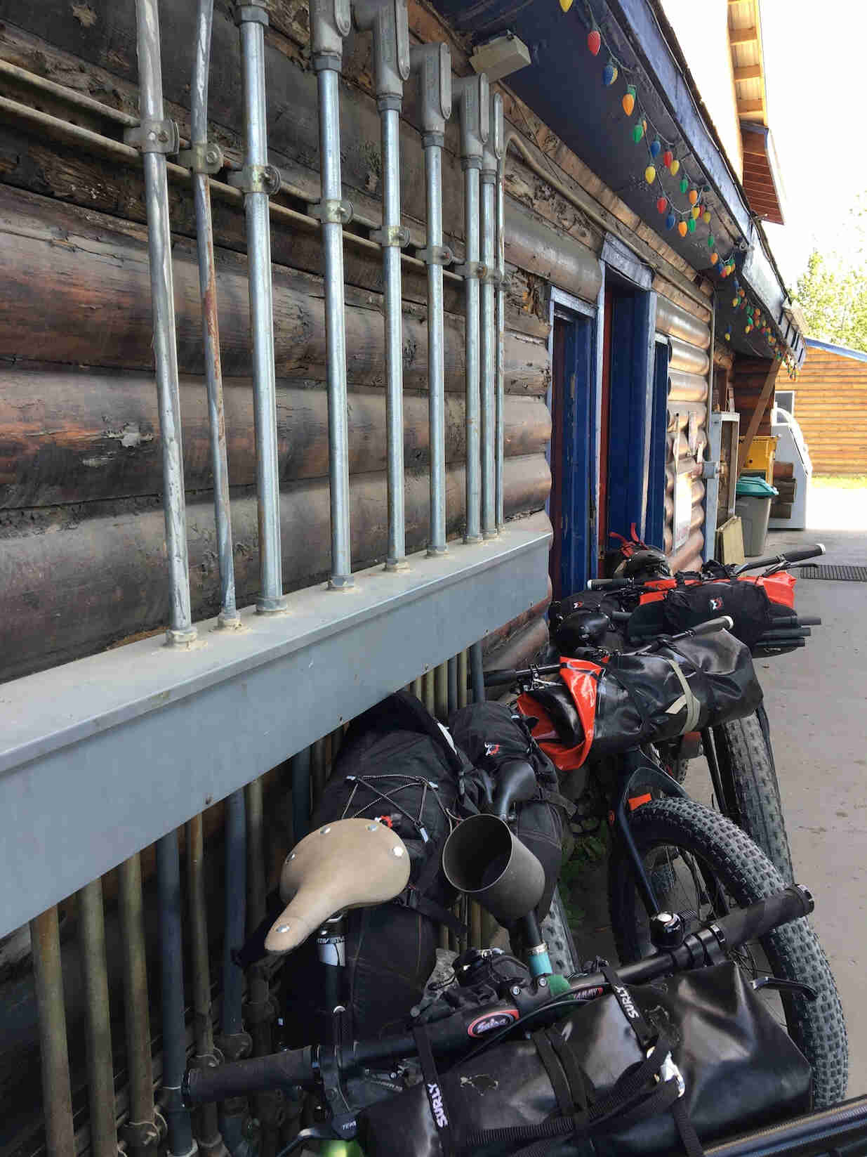Side view of fat bikes lined up against the wall outside of a log building