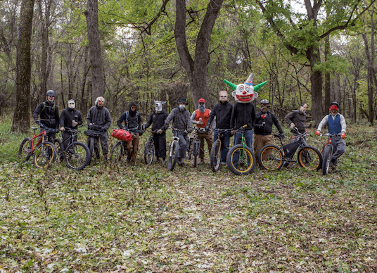 Front view of a group of cyclists standing with their bikes in the woods