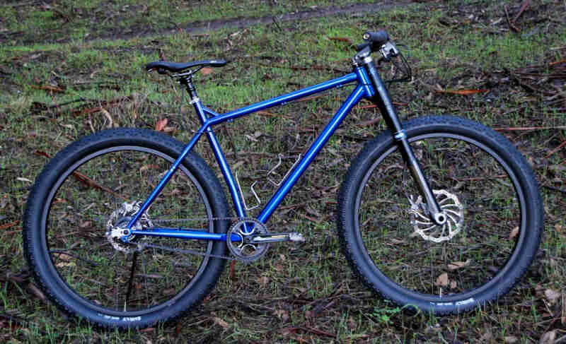 Right profile of a Surly Krampus bike, blue, parked on a grassy hill
