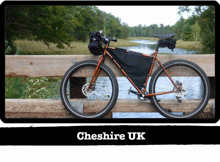 Left profile of a Surly Karate Monkey bike, copper, in front of a wood bridge rail - Cheshire UK tag below image