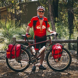 Right side of a Surly bike with red gear packs, and a cyclist standing behind, in the woods
