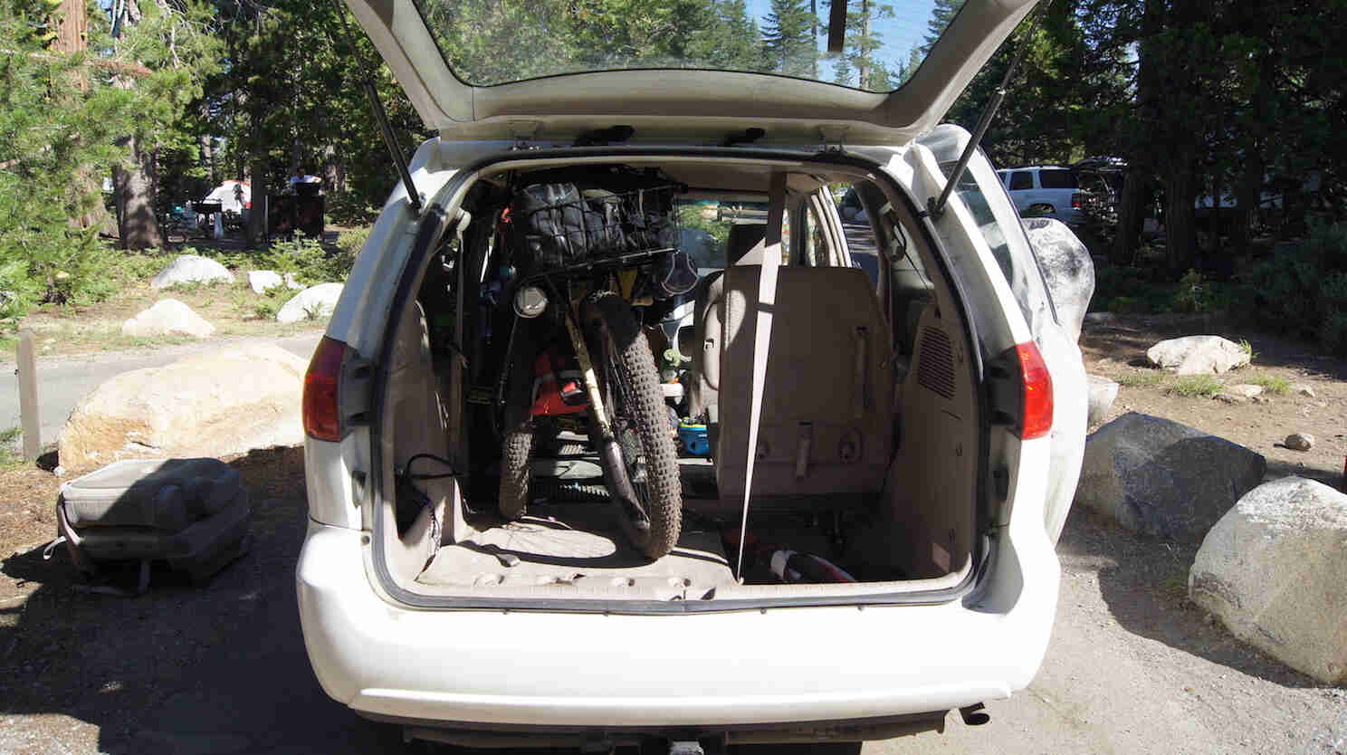 Rear view of a minivan with the back door open, with bike loaded in back