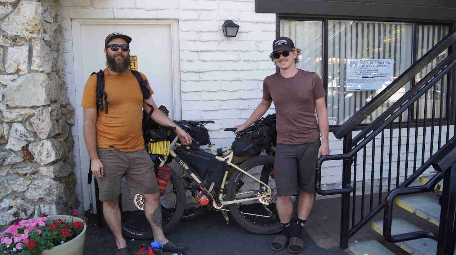 Front view of two cyclists standing with Surly fat bikes, in front of a motel room