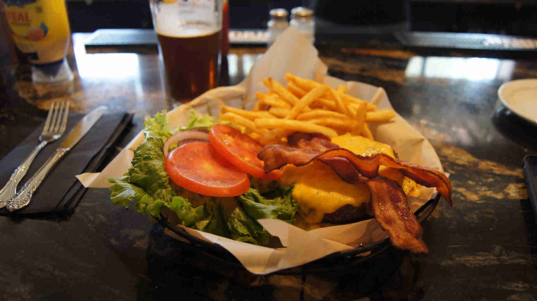 A food basket, with burger and fries, on a bar top